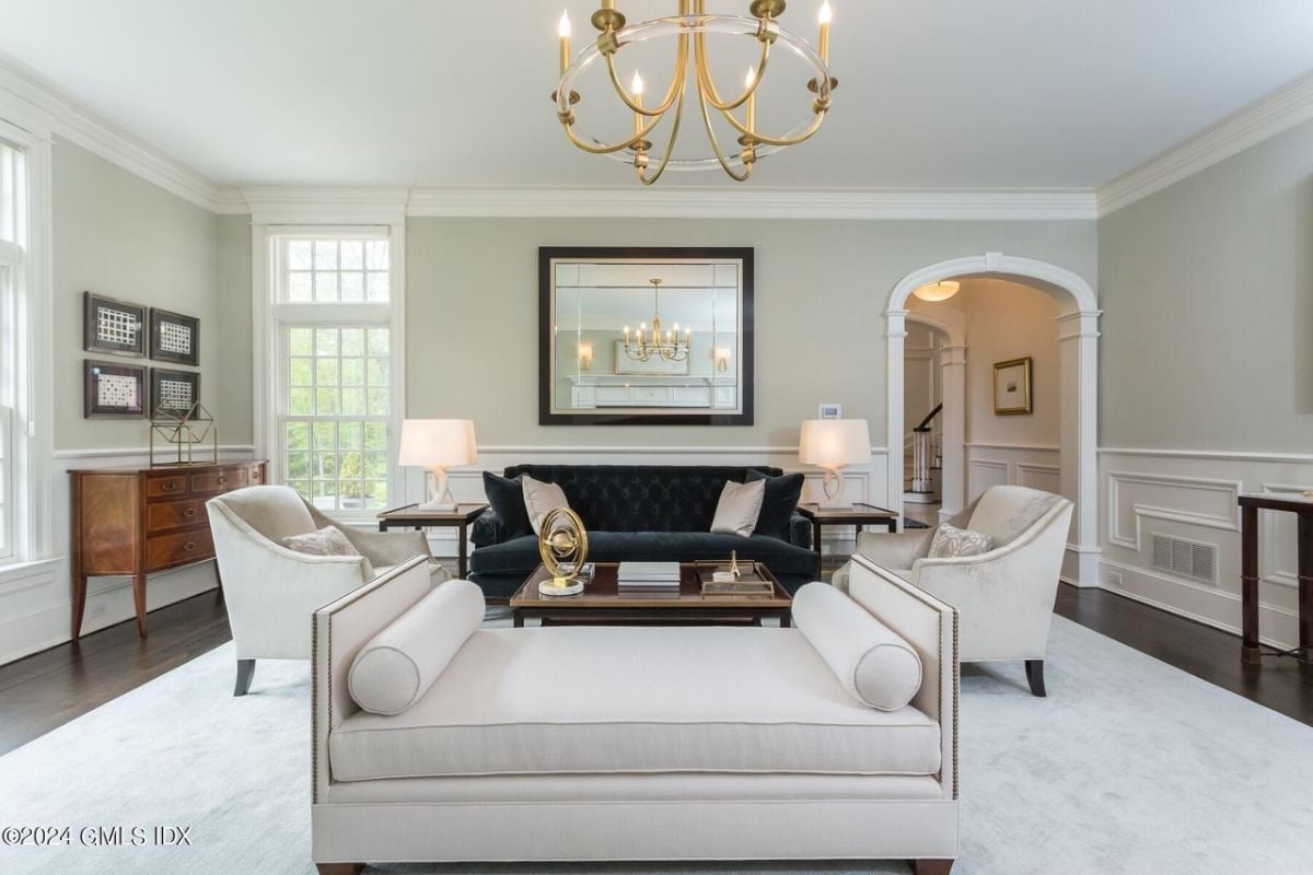 A living room with windows, a chandelier, a cabinet, couches, and a center table.