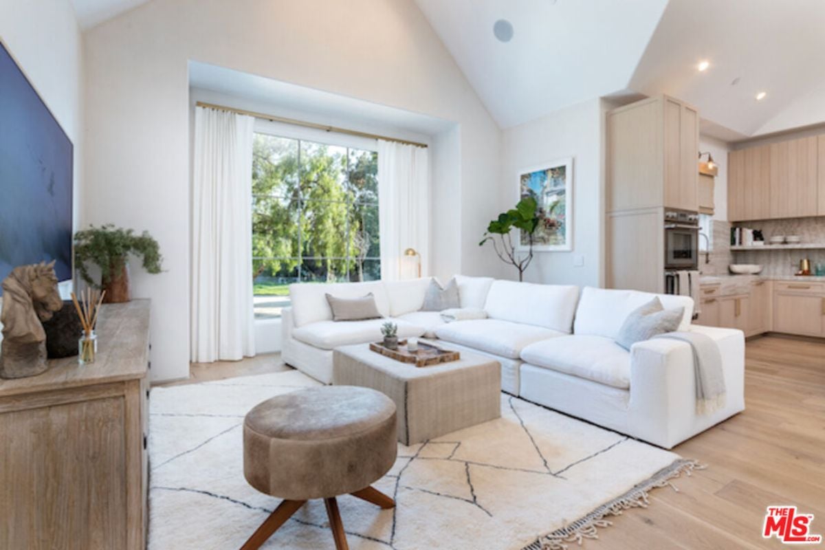A living room featuring a TV, cabinet, rug, white couch, chair, and center table.