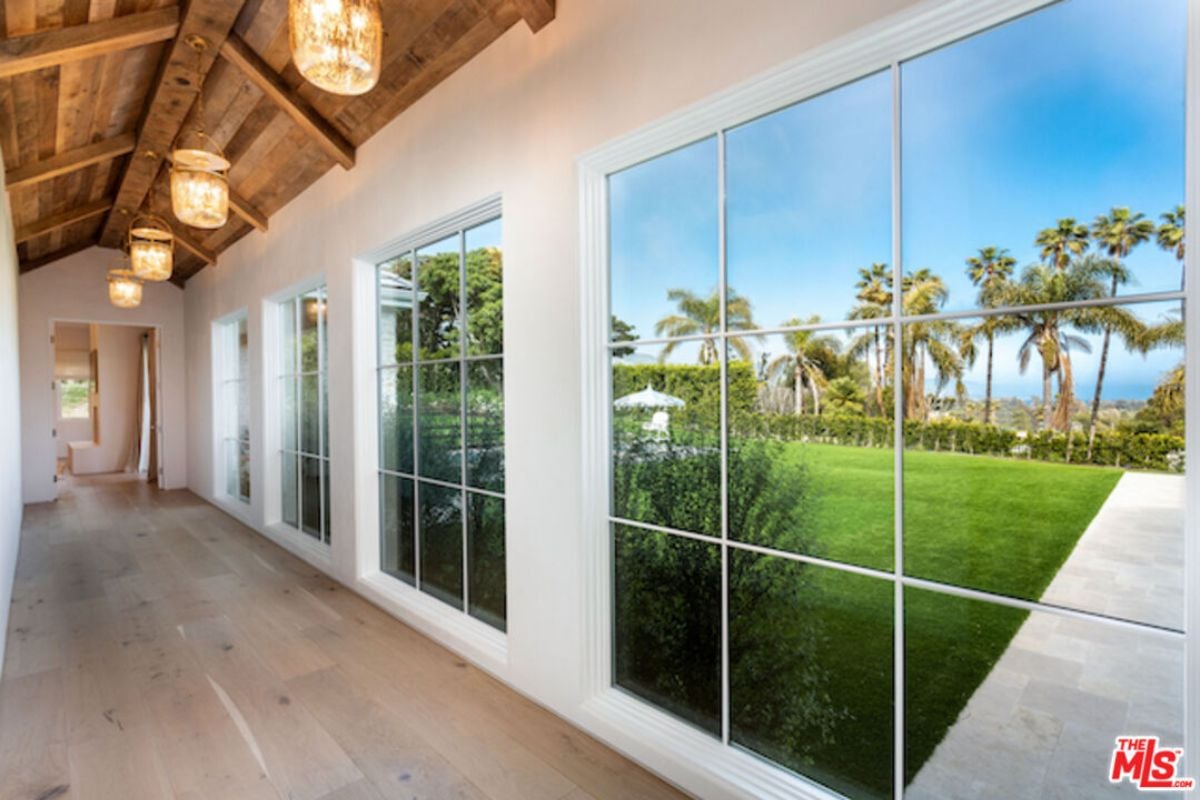 A hallway with vaulted ceilings, windows, and wooden flooring.