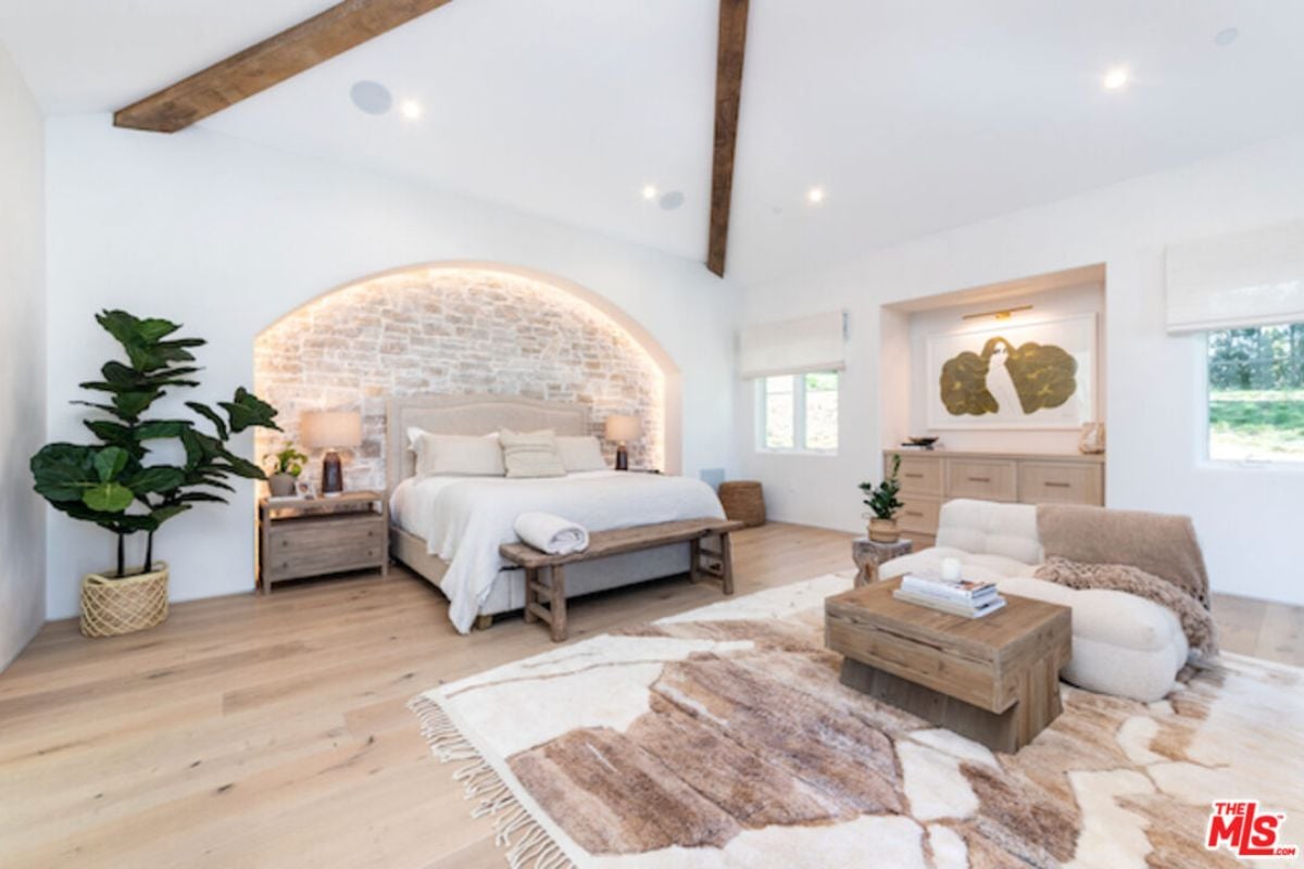 A bedroom with a bed, potted plant, cabinet, couch, coffee table, and nightstand.