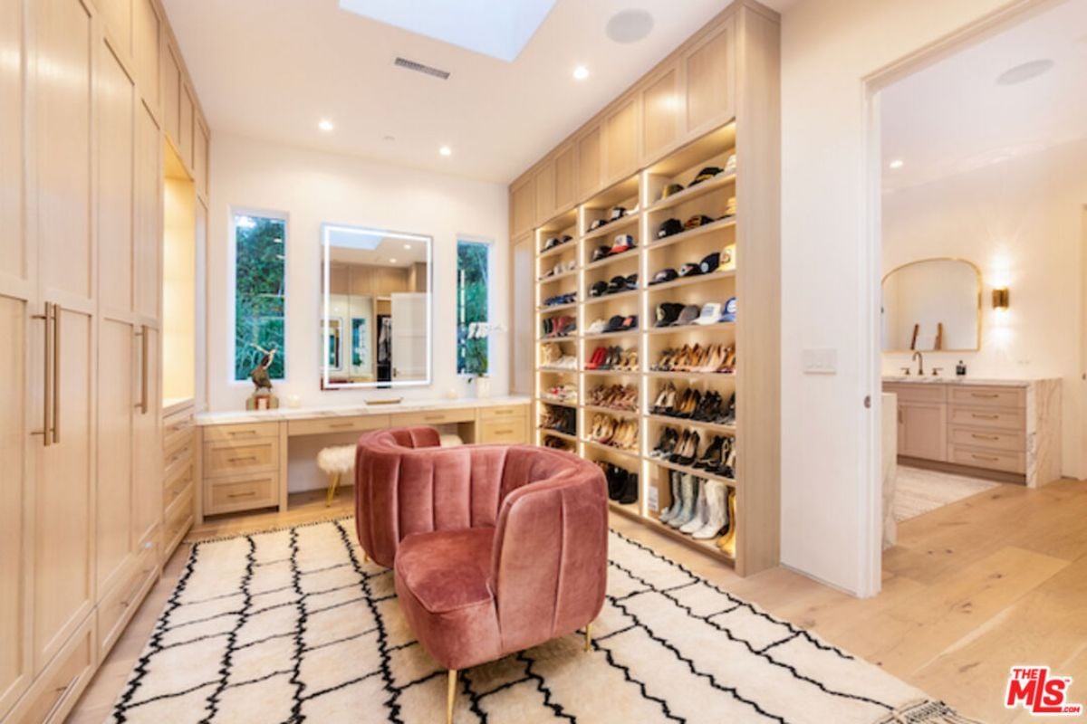 A powder area with mirror, desk, chair, cabinet, and shelf.