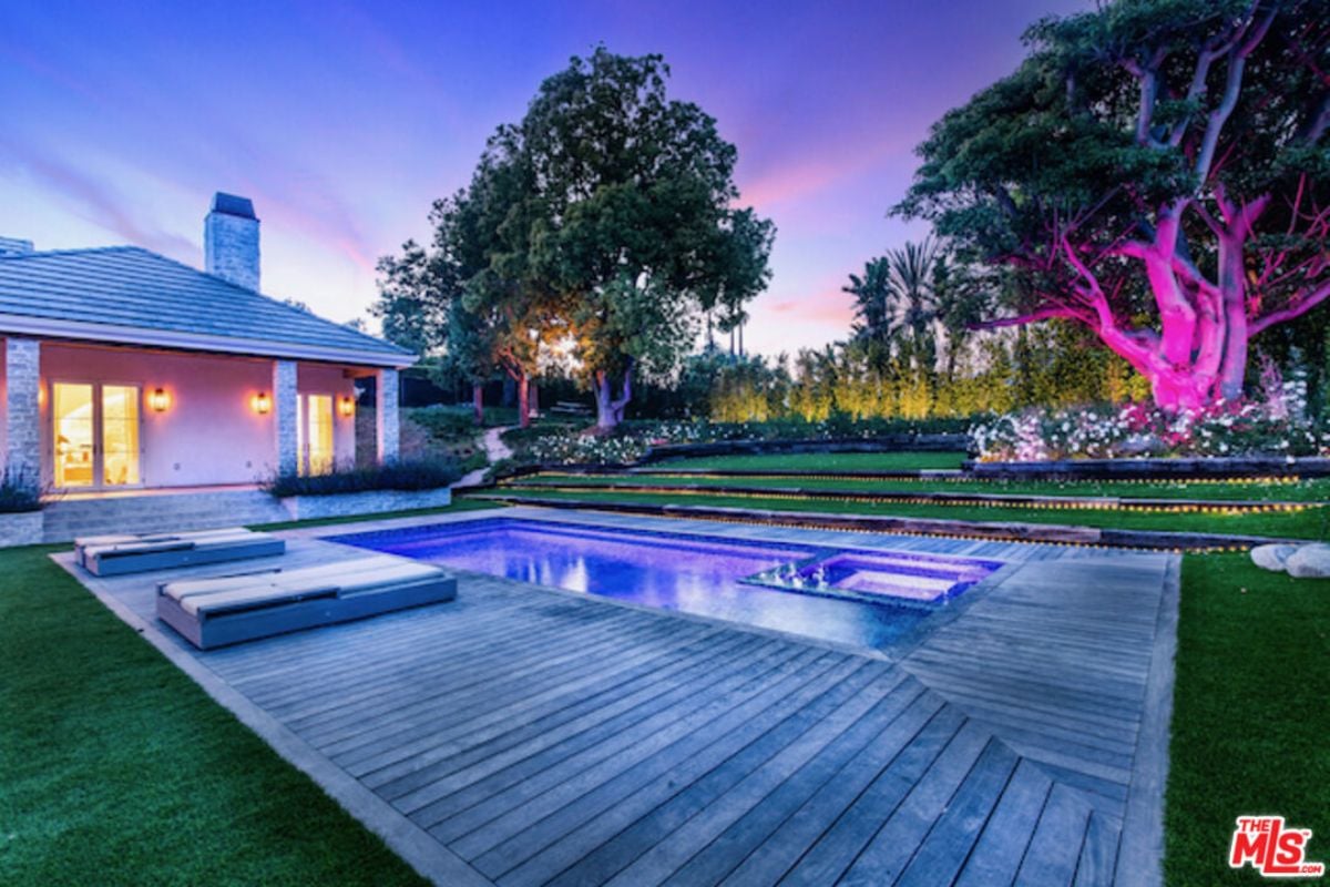 A swimming pool surrounded by a wooden deck with comfortable chairs.