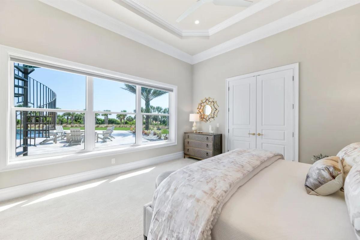 Bedroom with a large bed, glass windows and carpet flooring.