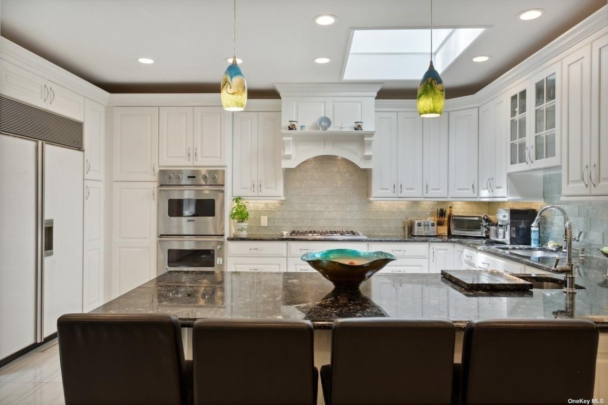 Kitchen with stainless-steel appliances, a spacious granite counter breakfast bar and custom cabinetry.