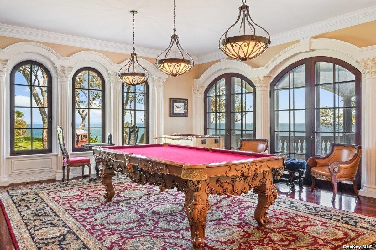 Billiards room with a large rug and glass windows.