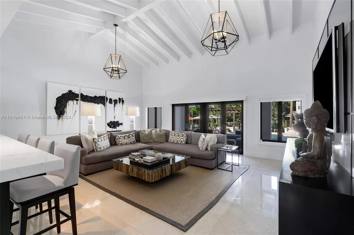 Living room with couches, tile flooring and glass doors.