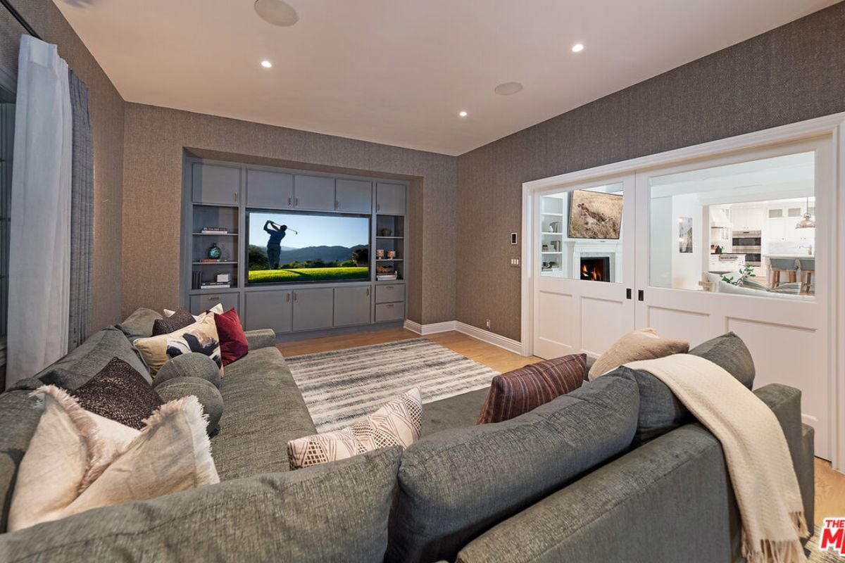 A family room with a TV, a cabinet, a rug, and an L-shaped couch.