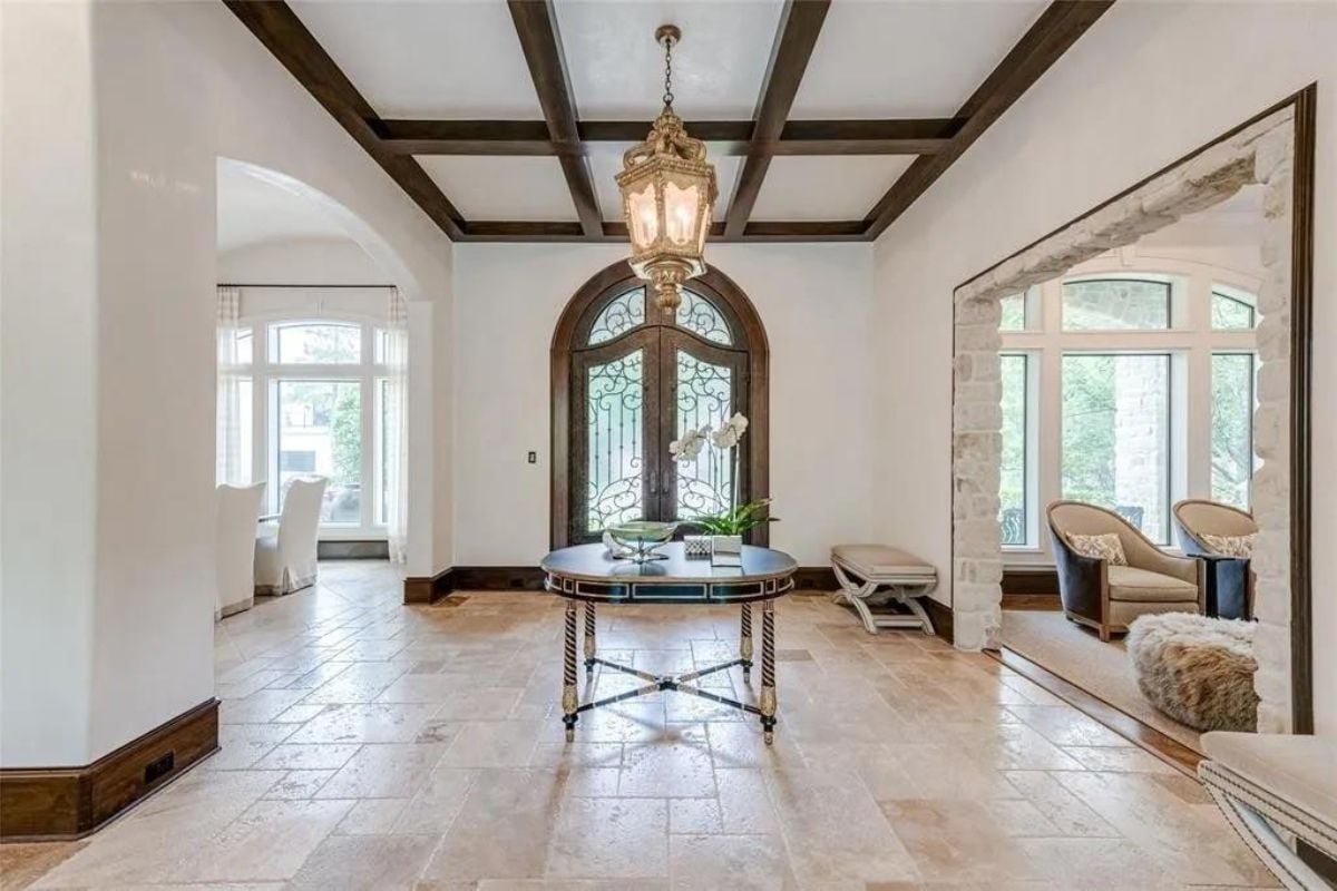 A foyer with an exposed beam ceiling, chandelier, and a round center table.