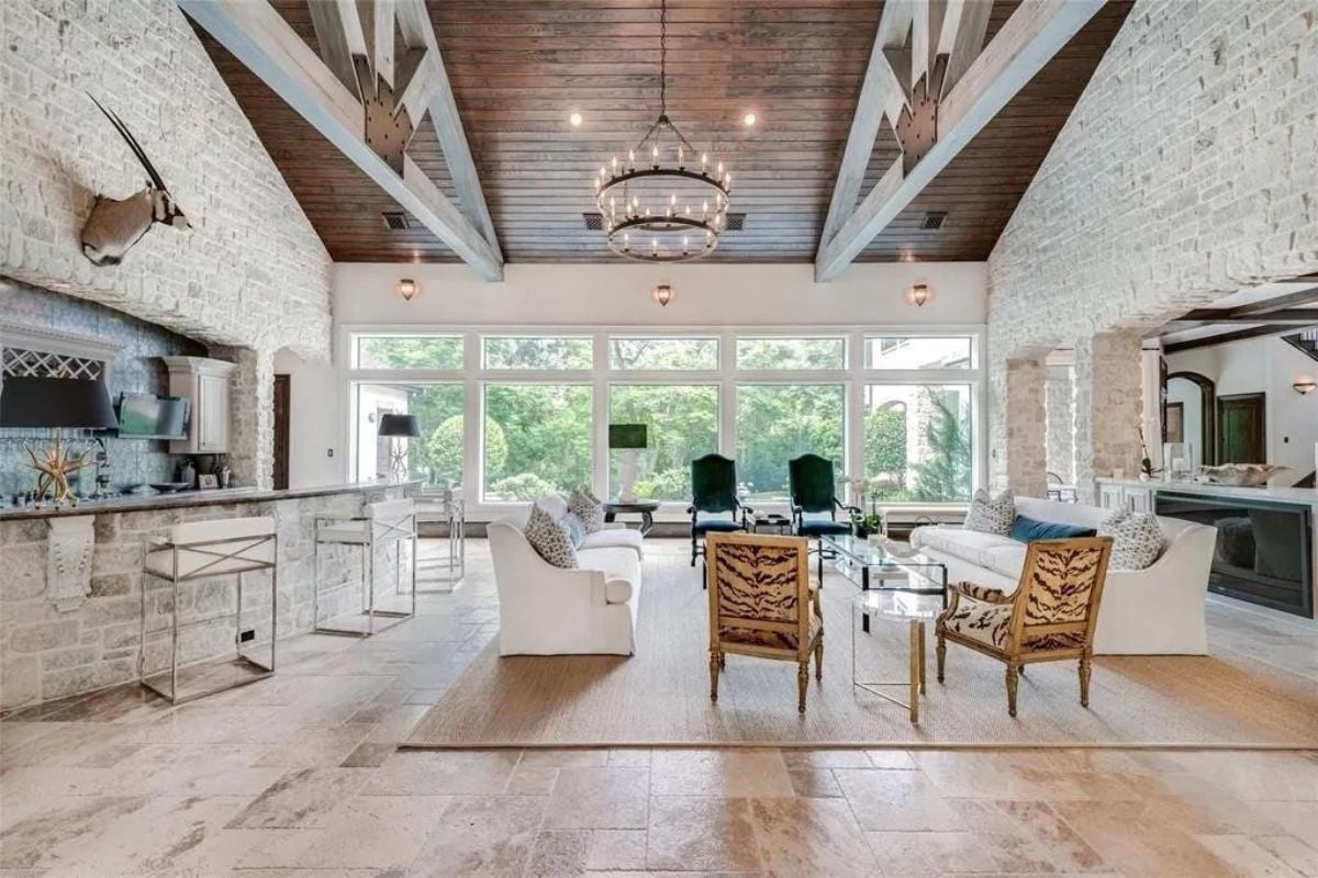 A great room with a vaulted ceiling, chandelier, bar, living area, and kitchen.