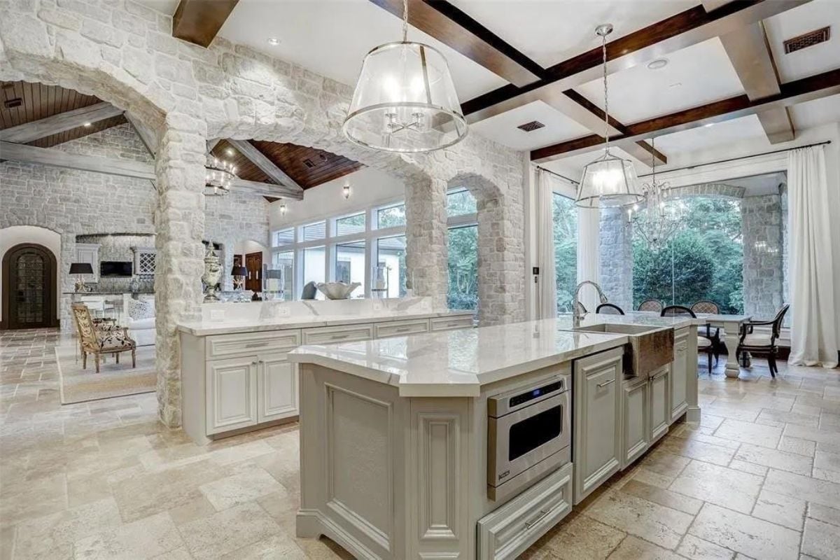 A kitchen with an exposed beam ceiling, countertops, sink, and cabinets.