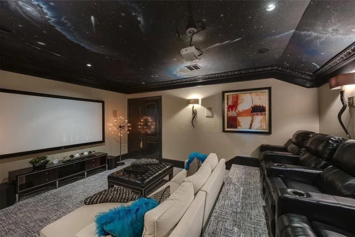 A home theater with a painted ceiling, large screen, center table, painting, and couches.
