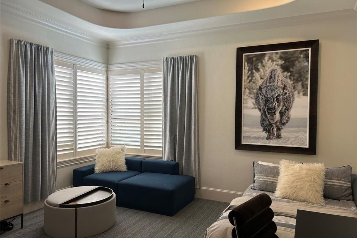 A bedroom with a bed, windows, cabinet, couch, and round center table.