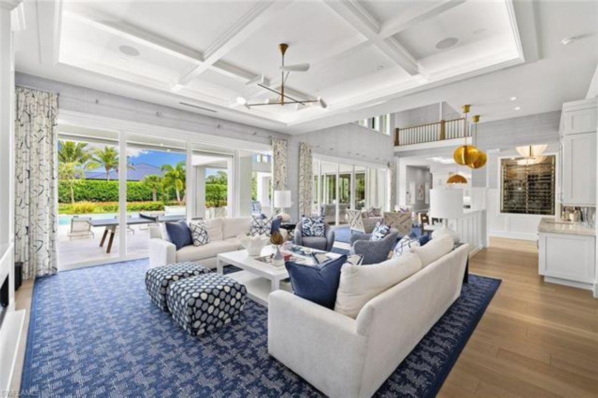 A living room with a rug, white couches, chairs, and a center table.