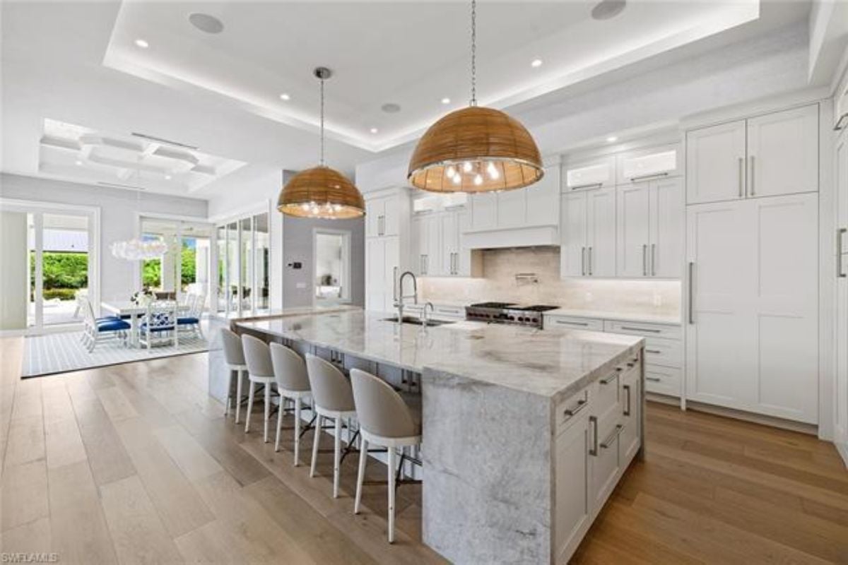 A kitchen with countertops, chairs, a sink, and cabinets.
