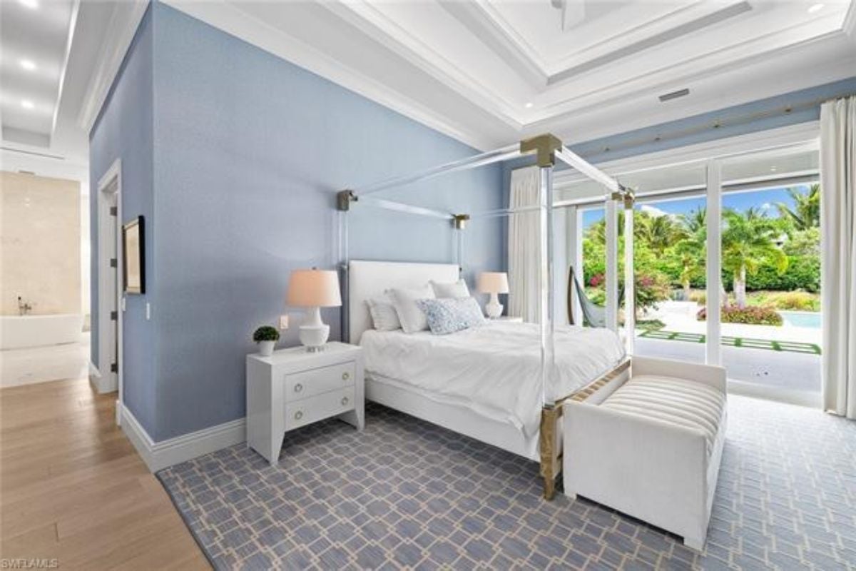 A bedroom with a canopy bed, nightstands, lampshades, and a rug.