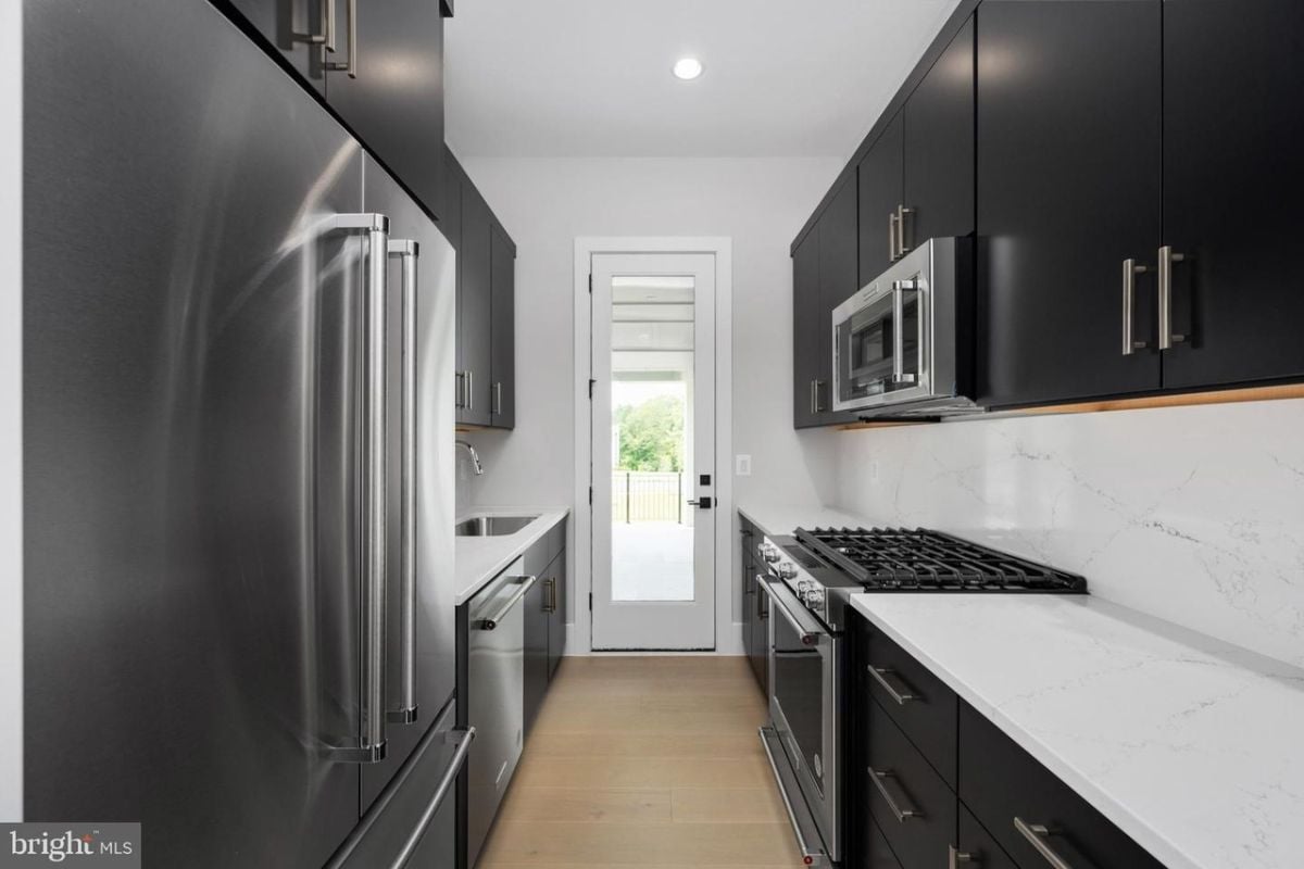 A kitchen with countertops, cabinets, sink, and kitchen appliances.