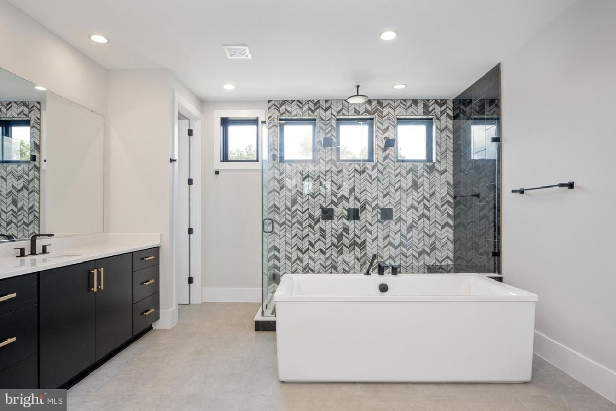 A bathroom with a vanity, mirror, cabinet, bathtub, and shower room.