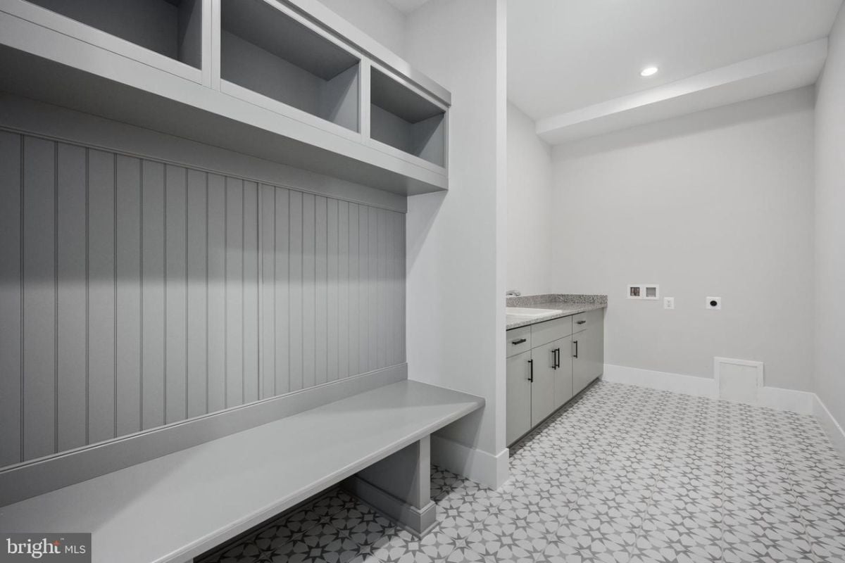 A mudroom with a tiled floor, countertop, cabinets, and bench.