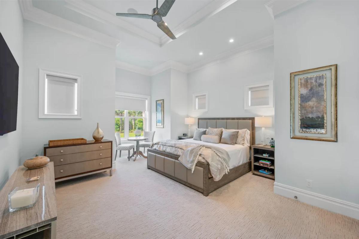 Bedroom with a large bed, glass windows and carpet flooring.