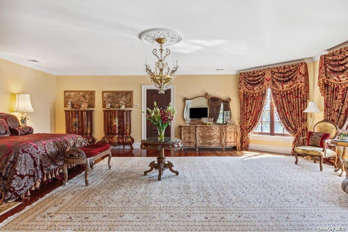 Bedroom with a chandelier, hardwood floors and a large rug.