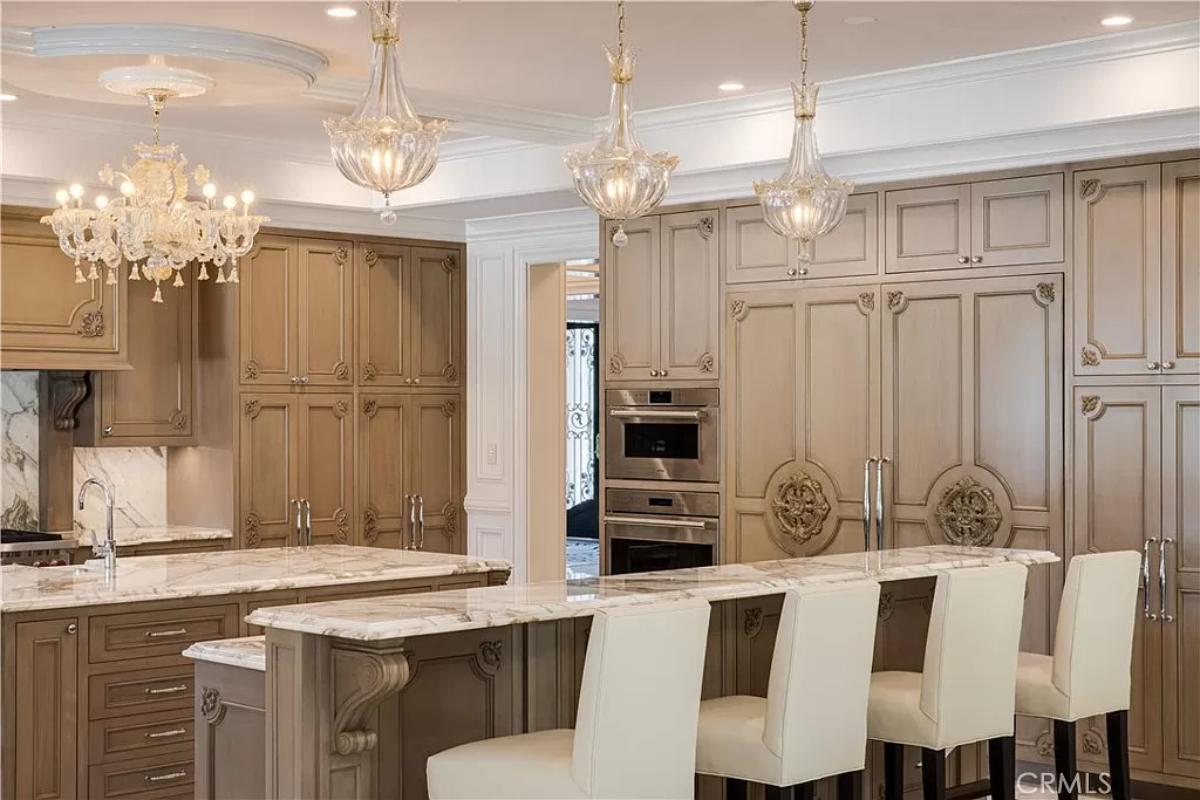 Kitchen with chandeliers, custom cabinetry, counter breakfast bar and a center island prep area.