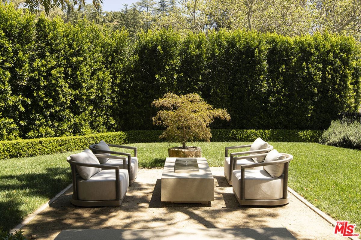 A patio with plants, chairs, and a center table.