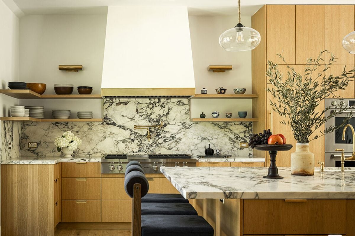 A kitchen with an island, chairs, a sink, cabinets, countertops, and kitchen appliances.