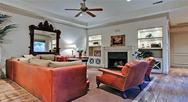Family room with leather seats and a fireplace flanked by white built-ins.