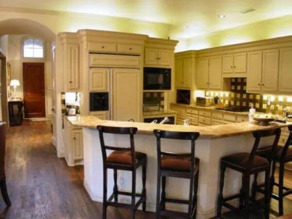 Kitchen with white cabinetry and an angled peninsula with bar seating.