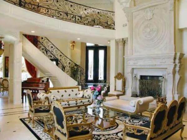 Living room with traditional chairs and a fireplace under a tall ceiling.