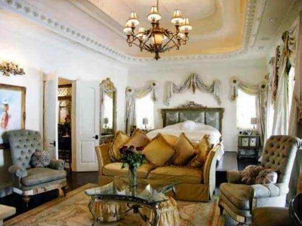 Primary bedroom with a custom bed and a sitting area illuminated by a warm chandelier.