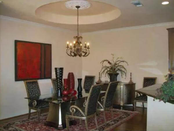 Dining room with a rectangular dining set and a warm chandelier that hangs from the tray ceiling.