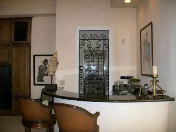 Wet bar with a curved counter and a wine cellar with an ornate door.