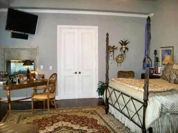 Primary bedroom with a four-poster bed, a wooden vanity, and a wall-mounted TV.