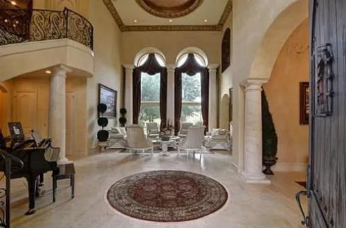 Foyer with a soaring ceiling, round columns, and limestone flooring topped by a round rug.
