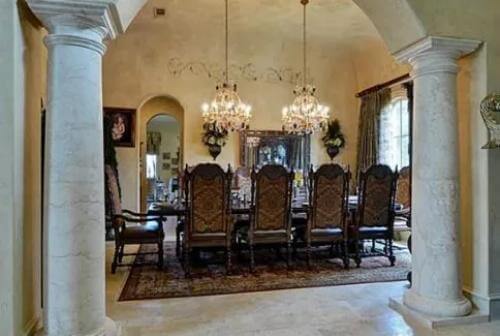 Dining room with a traditional dining set illuminated by a couple of chandeliers.