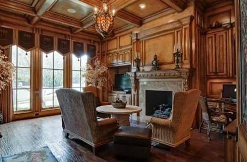 Study with a fireplace and wingback chairs under a coffered ceiling.