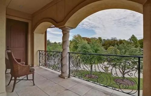 Balcony with cushioned chairs, a spiral column, and ornate wrought iron railings.