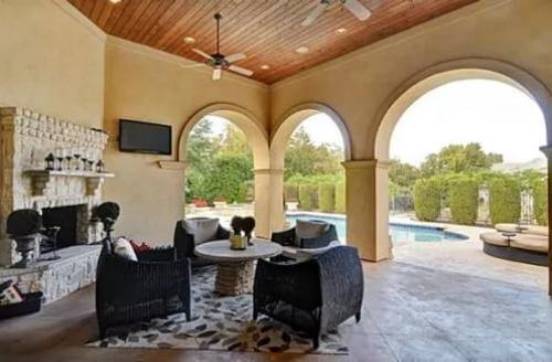 Covered porch with a stone fireplace and wicker chairs surrounding the round table.