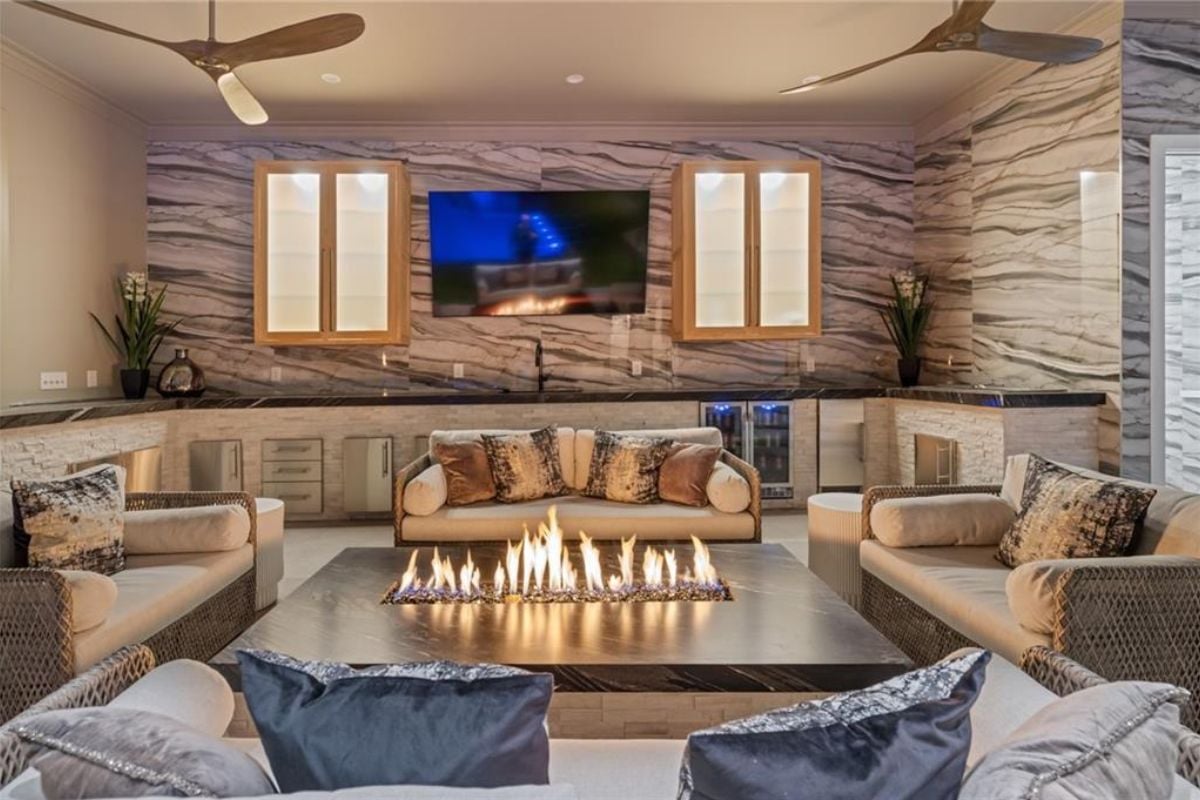 A living room with couches, a coffee table, a TV, a sink, and a countertop.