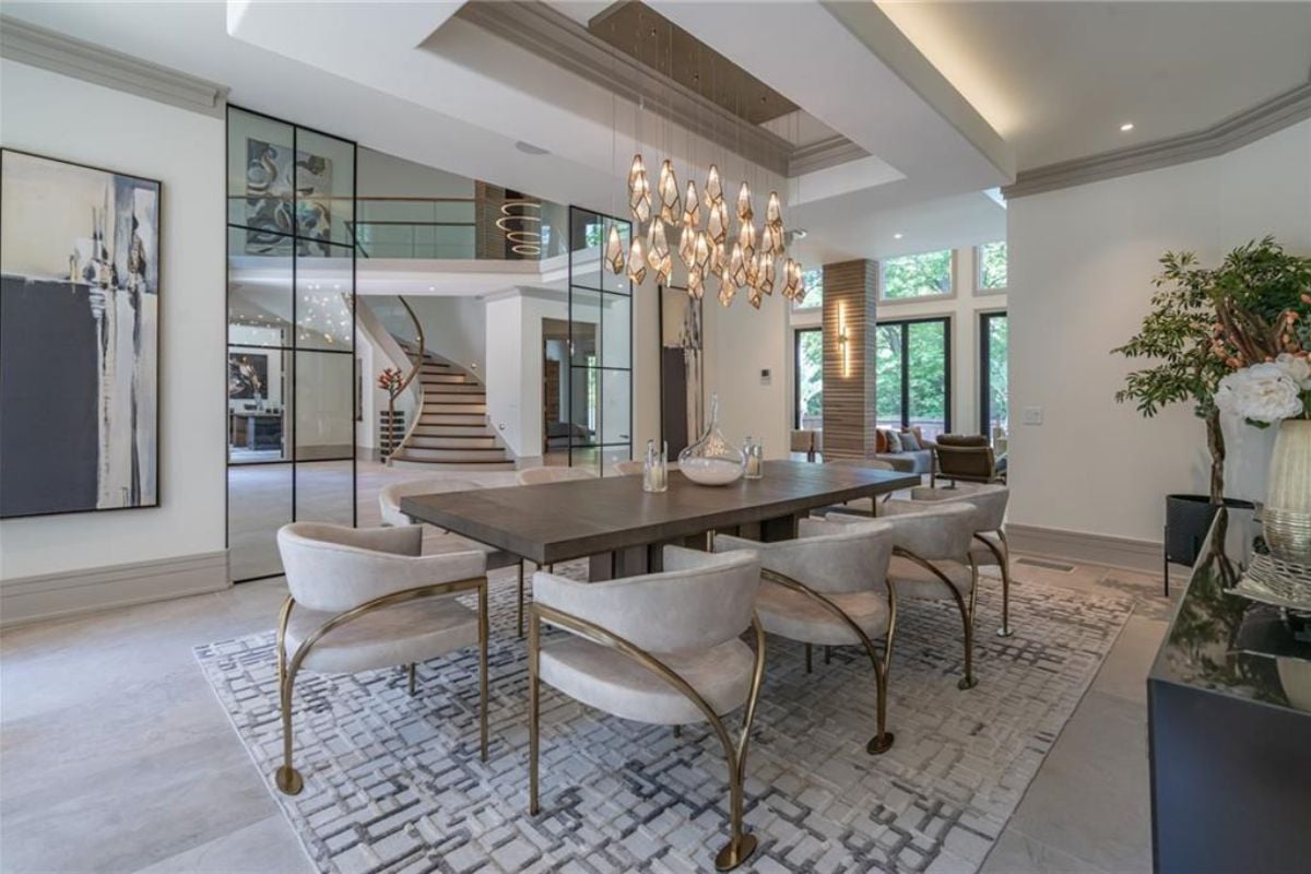 A dining room with a chandelier, a mirror, a cabinet, a rug, and a long dining table.