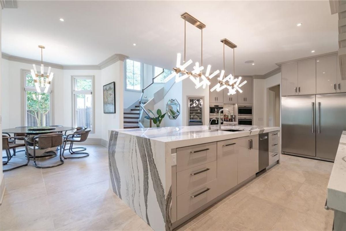 A kitchen with countertops, a sink, cabinets, kitchen appliances, and a round table surrounded by chairs.