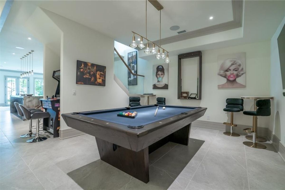 A game room with stools, a table, and a pool table.