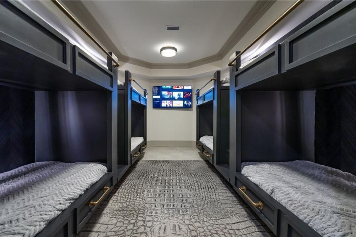 A bedroom with a TV and four double-decker beds.