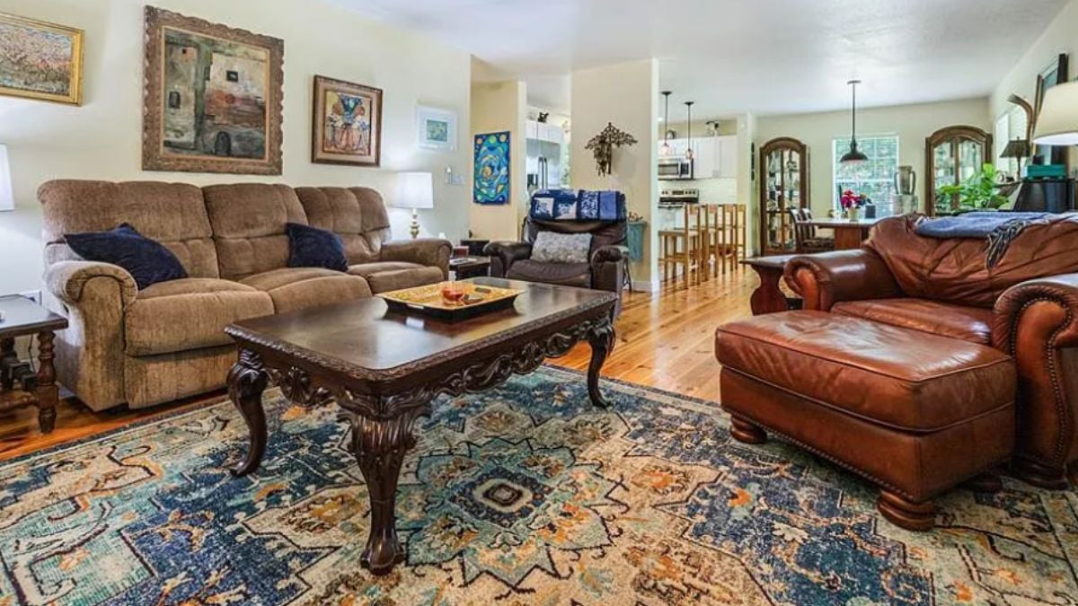 A living room with paintings, chairs, a couch, a rug, and a center table.