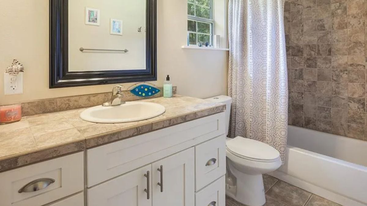 A bathroom with a vanity, mirror, cabinets, a toilet, and a bathtub.