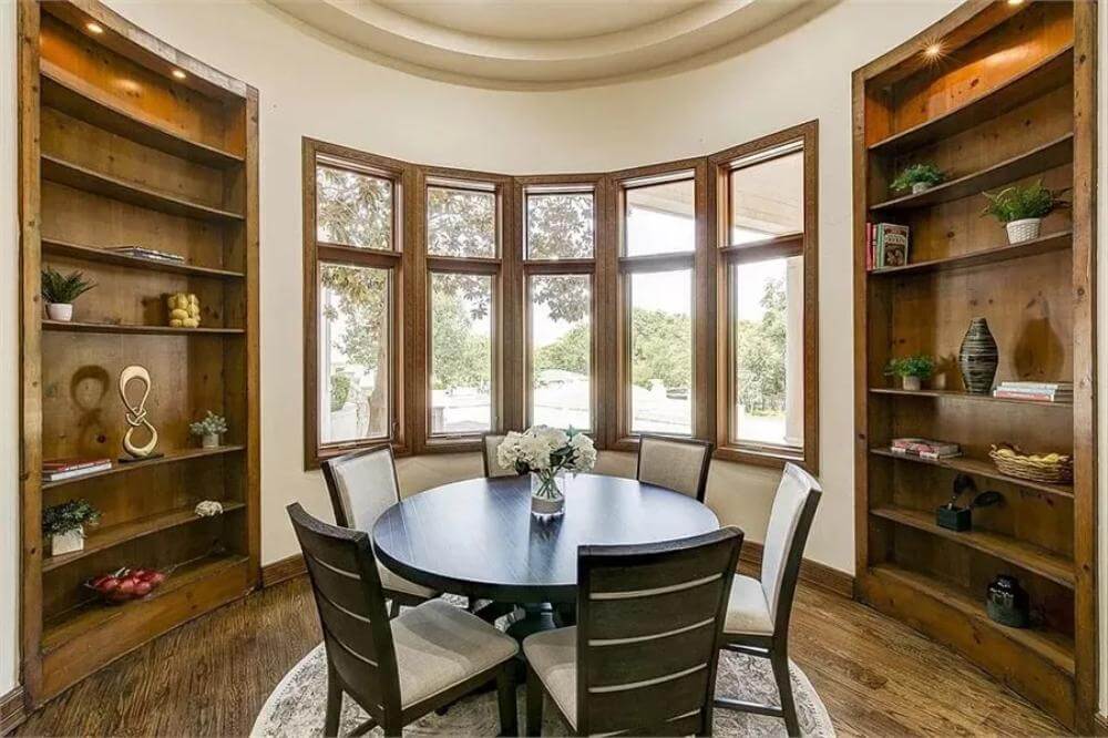 cozy dining nook with bay windows and custom shelving