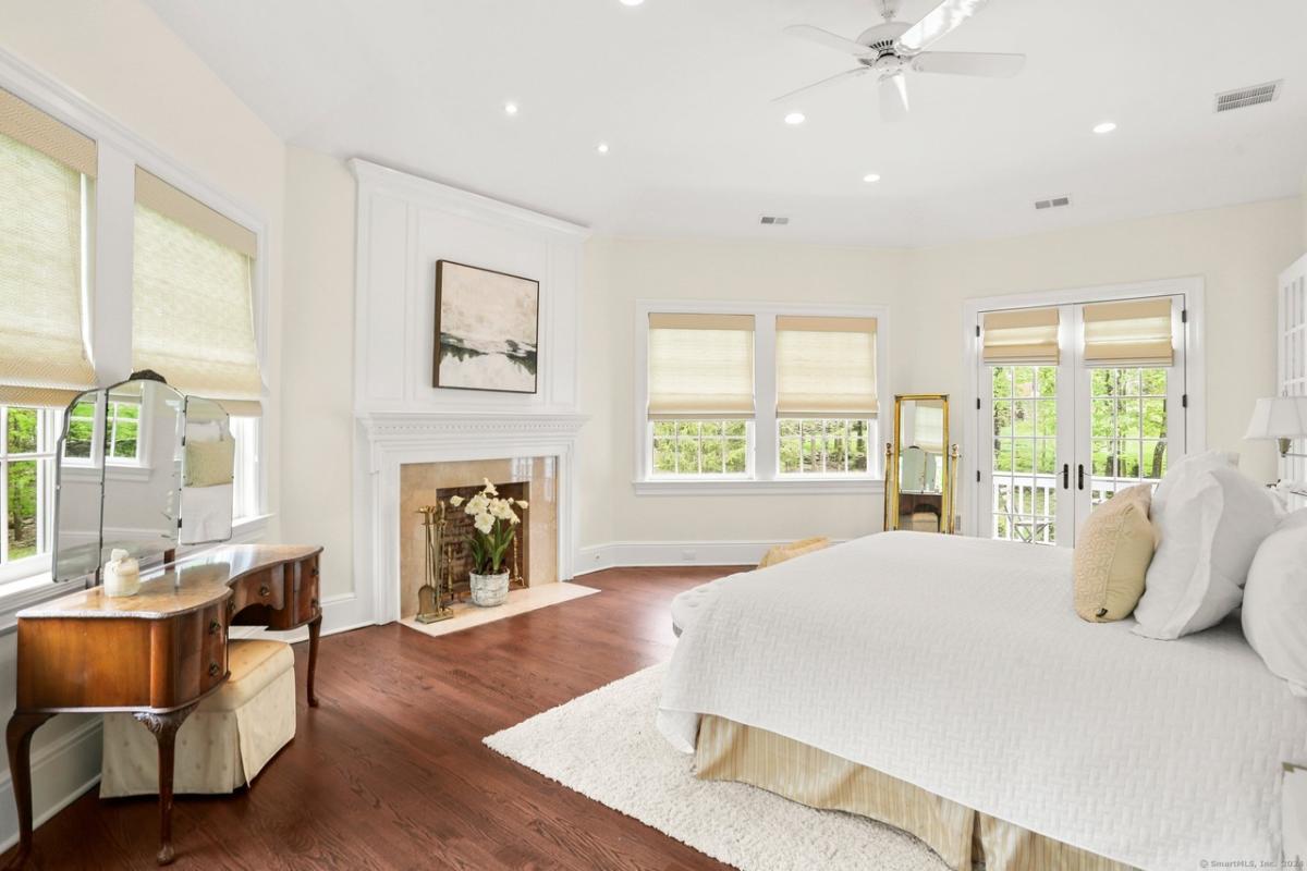 Bedroom with a large bed, a fireplace and hardwood floors.