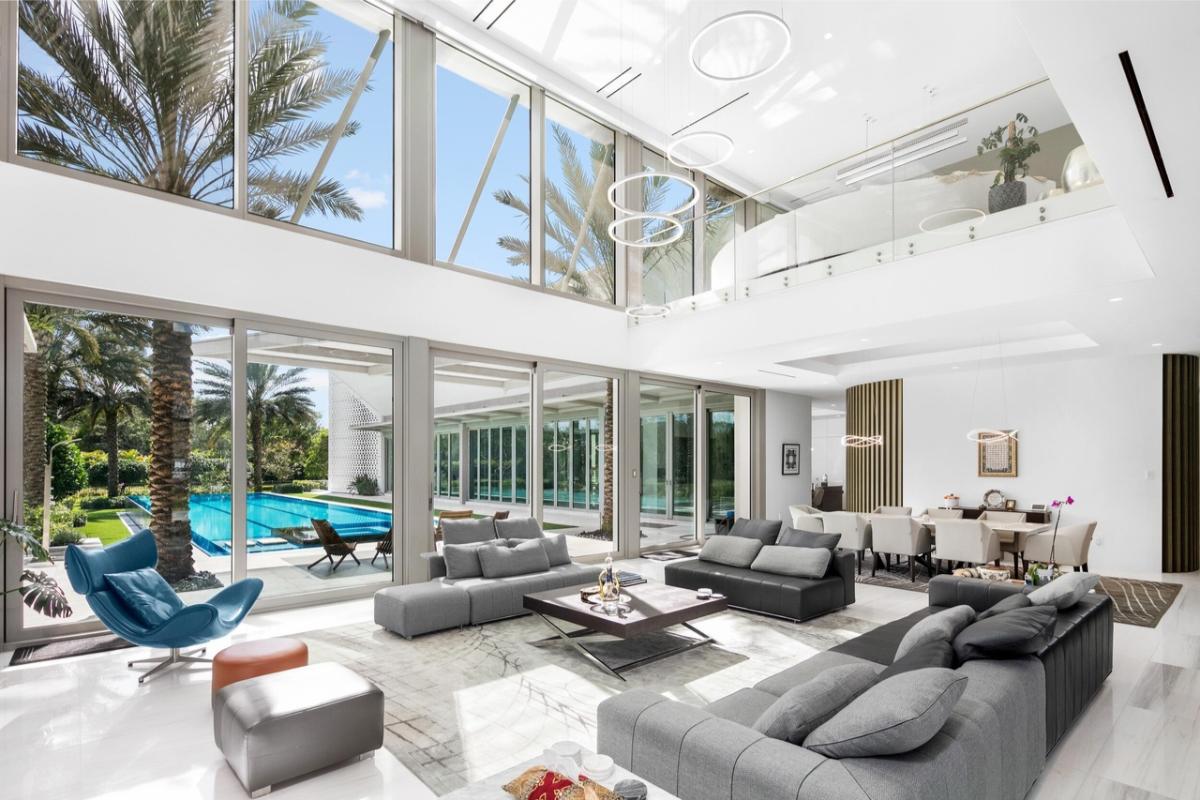 Living room with high ceilings, glass walls and glass doors.