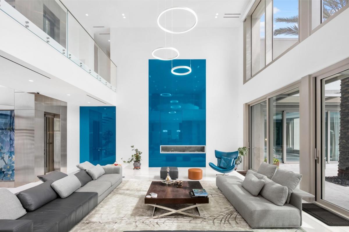 Living room with high ceilings, glass walls and glass doors.